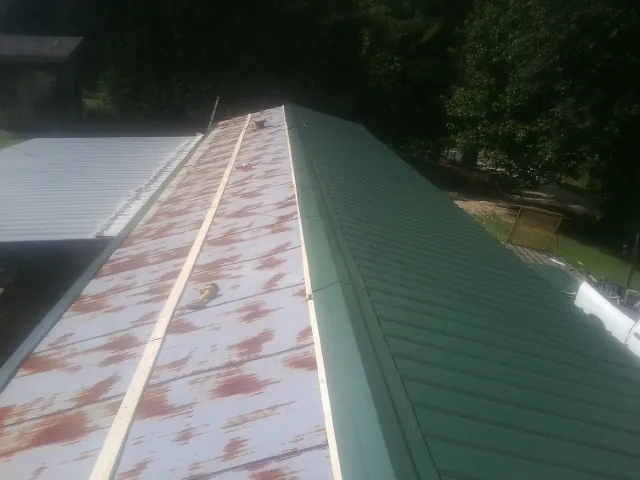 Old rusted panels beside newly installed green metal roofing — Wind Damage Roof Repair by Roofing Brothers in Fort Lawn