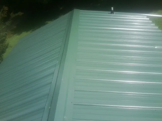 New green metal panels meeting at the ridge of a roof — Flat Roof Repair work by our crew in Fort Lawn