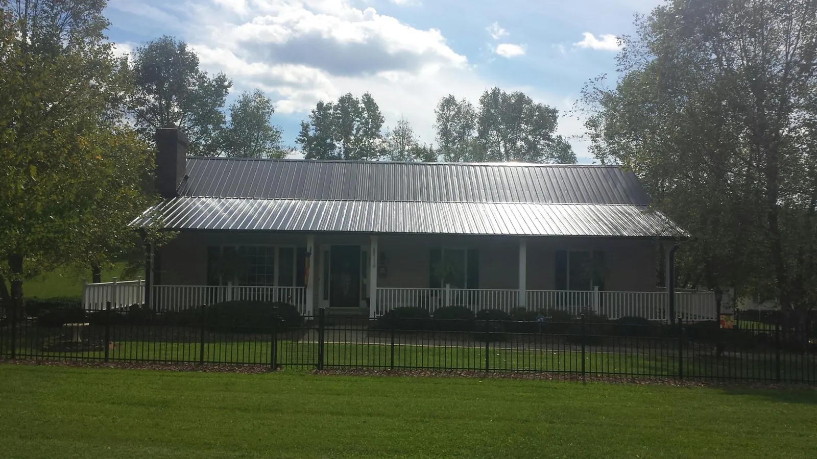 Gray metal roof on a brick ranch with a full width front porch — Gutter Guard Installation work by our crew in Fort Lawn
