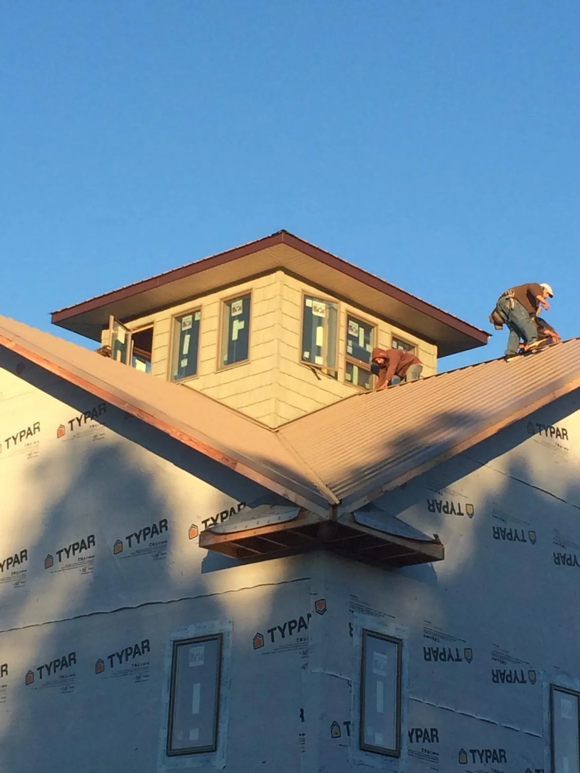 Roofers working around a rooftop cupola on a new metal roof at sunset — Roof Waterproofing in Fort Lawn by Roofing Brothers